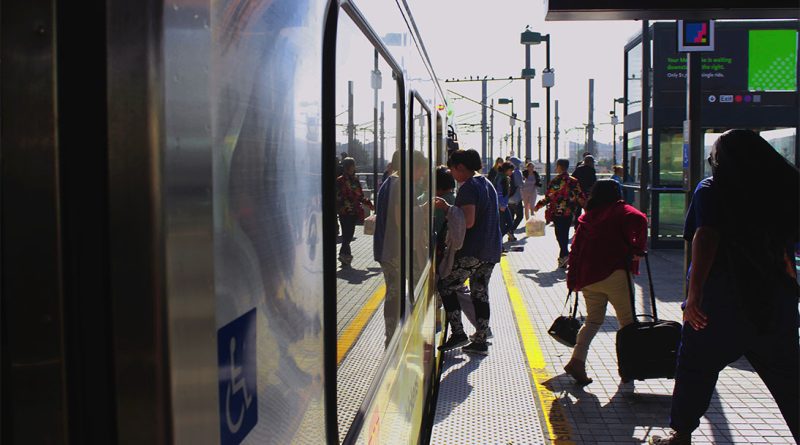Close up image of a passenger train at a station with numerous people going off and on board to support us passenger train article