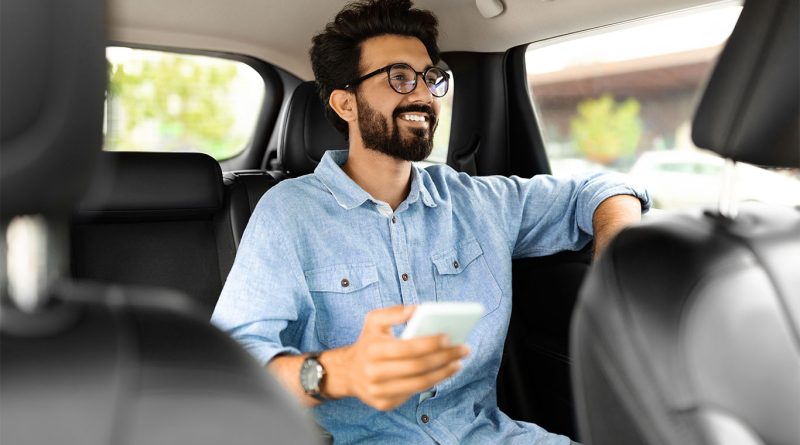Image of a man sat in the back of a leather interior car with his white mobile phone in his hand to support A1 auto transport article