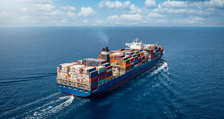 A large container cargo ship travels over calm, blue ocean