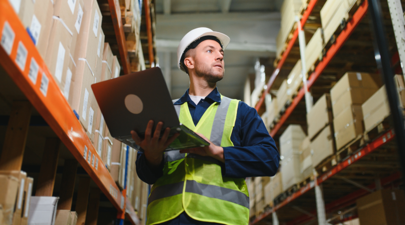 Logistics manager using logistics management software in a warehouse, optimizing inventory with transportation management logistics tools and logistics management solutions.