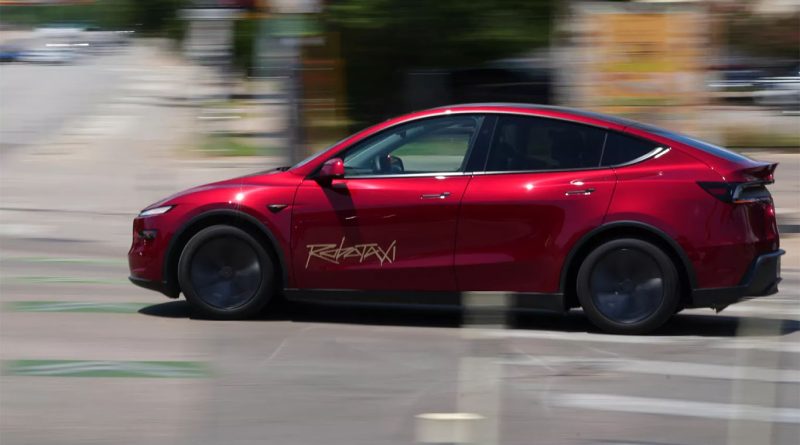 Red Tesla robotaxi driving through streets