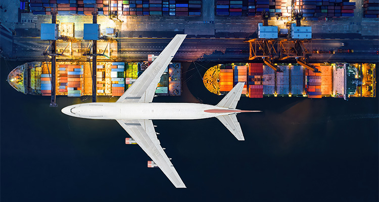 Air freight flying over container ships in a dock
