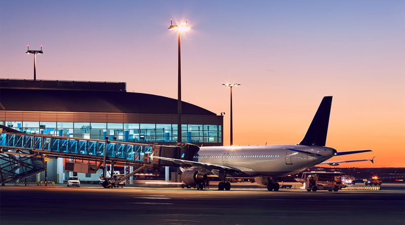 Passenger dragging suitcase at US airport looking at departure and arrival boards during flight delays